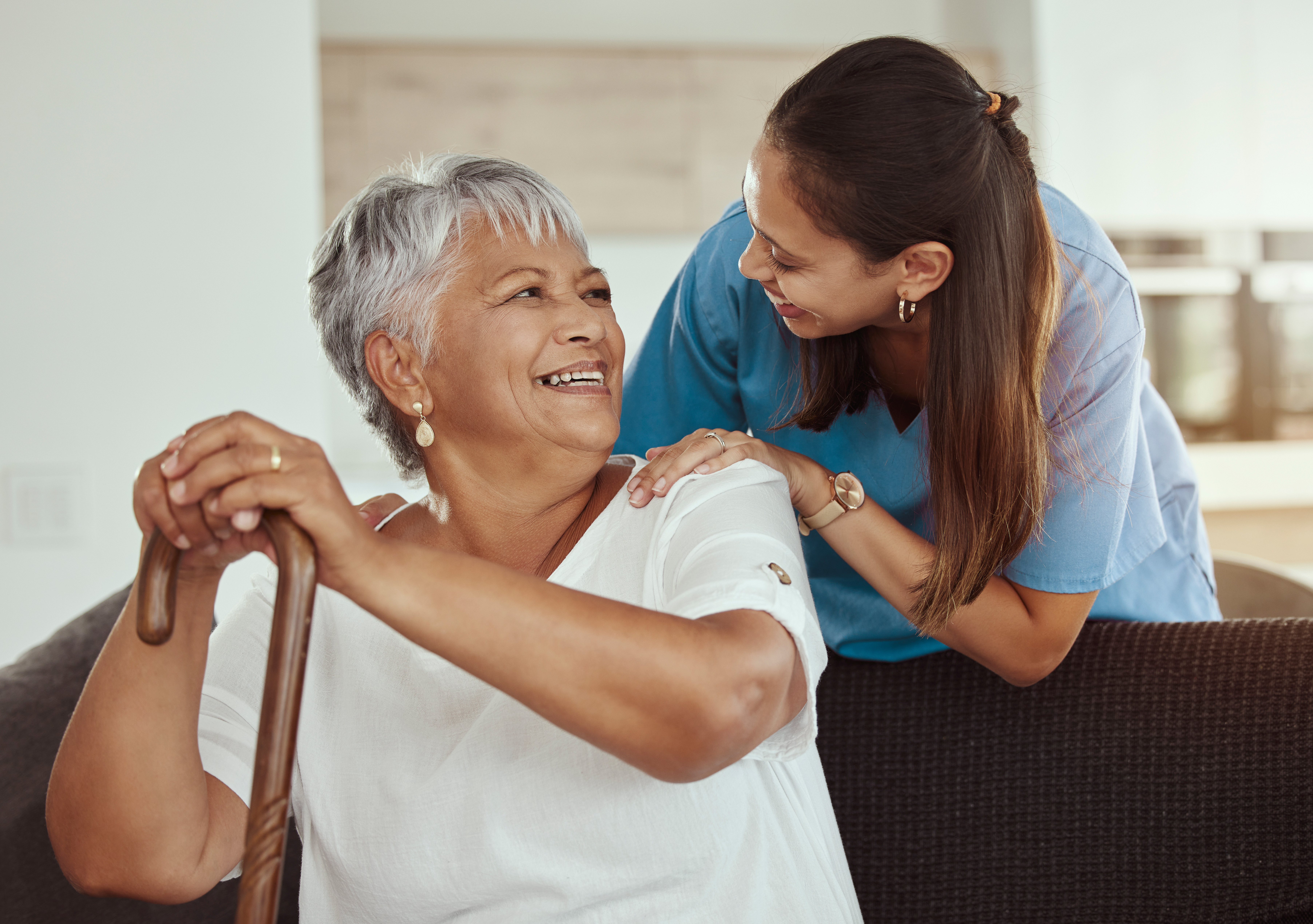 A female caregiver helping an elderly female patient.